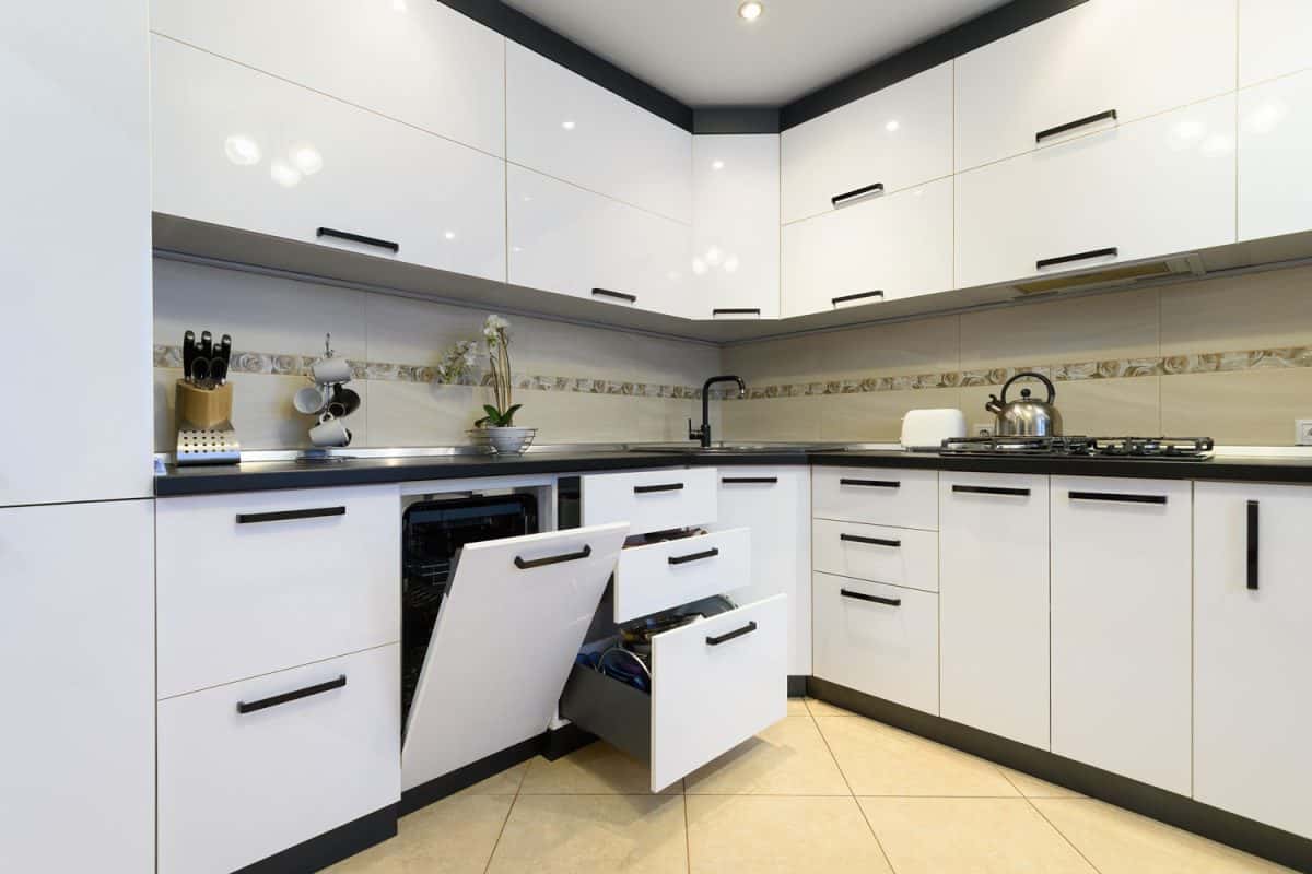 White cabinets and cupboards in a luxurious kitchen with a flushed dishwasher
