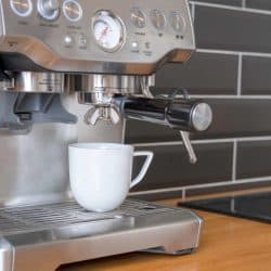 White cup stands in a espresso machine in the process of making coffee, Can You Make A Latte With An Espresso Machine?