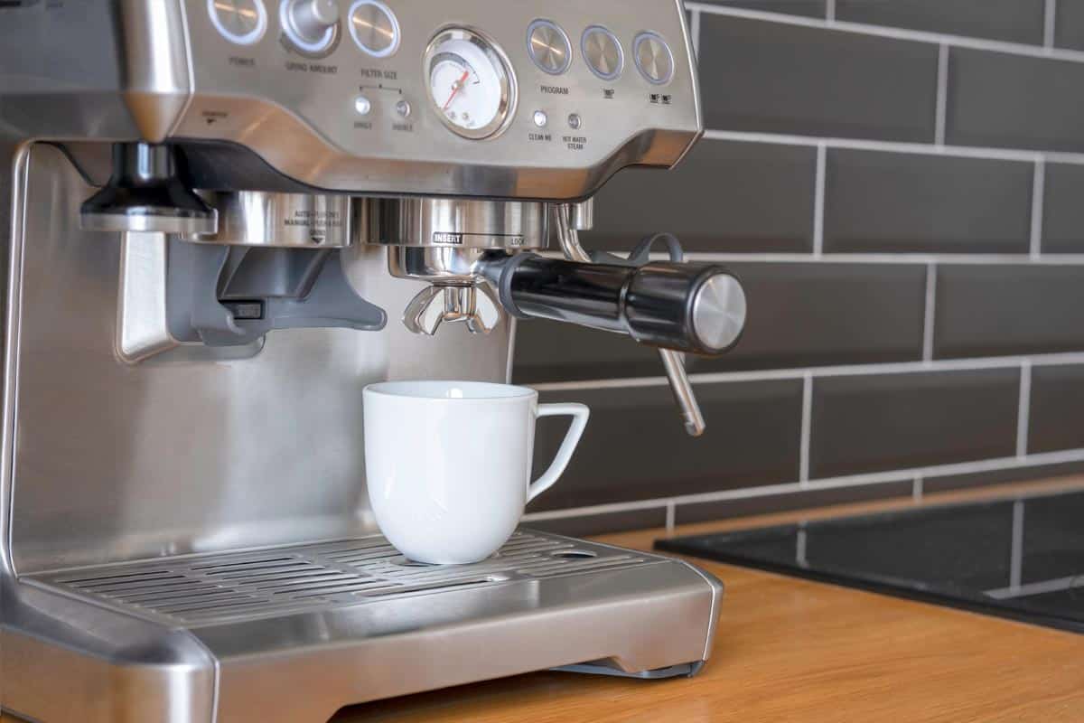 White cup stands in a espresso machine in the process of making coffee, Can You Make A Latte With An Espresso Machine?