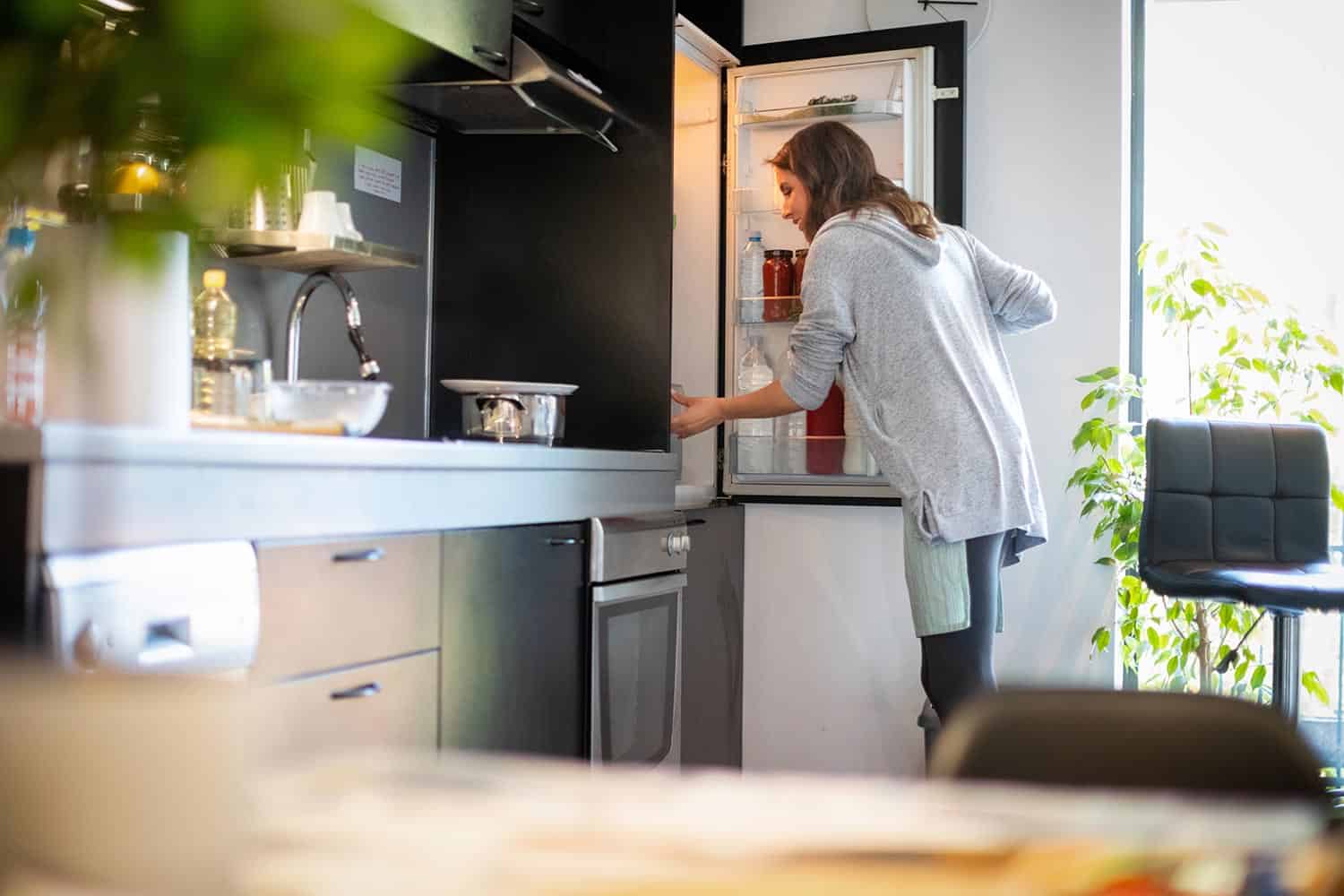 Woman opening fridge to find ingredients for lunch