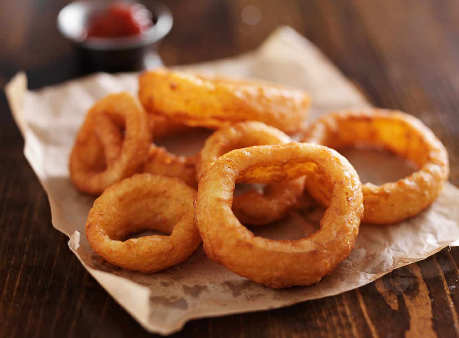 crispy onion rings with ketchup on parchment paper close up and in horizontal composition