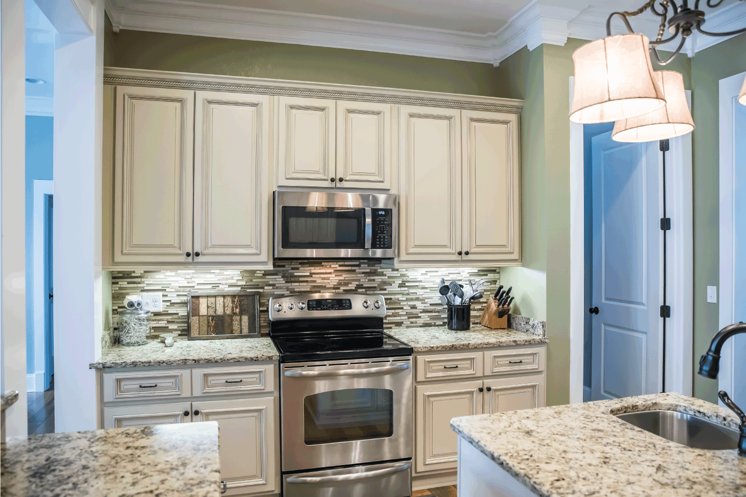 small appliance microwave in a green kitchen with cream colored cabinets in a new construction home with granite countertops and lots of cabinets and storage space