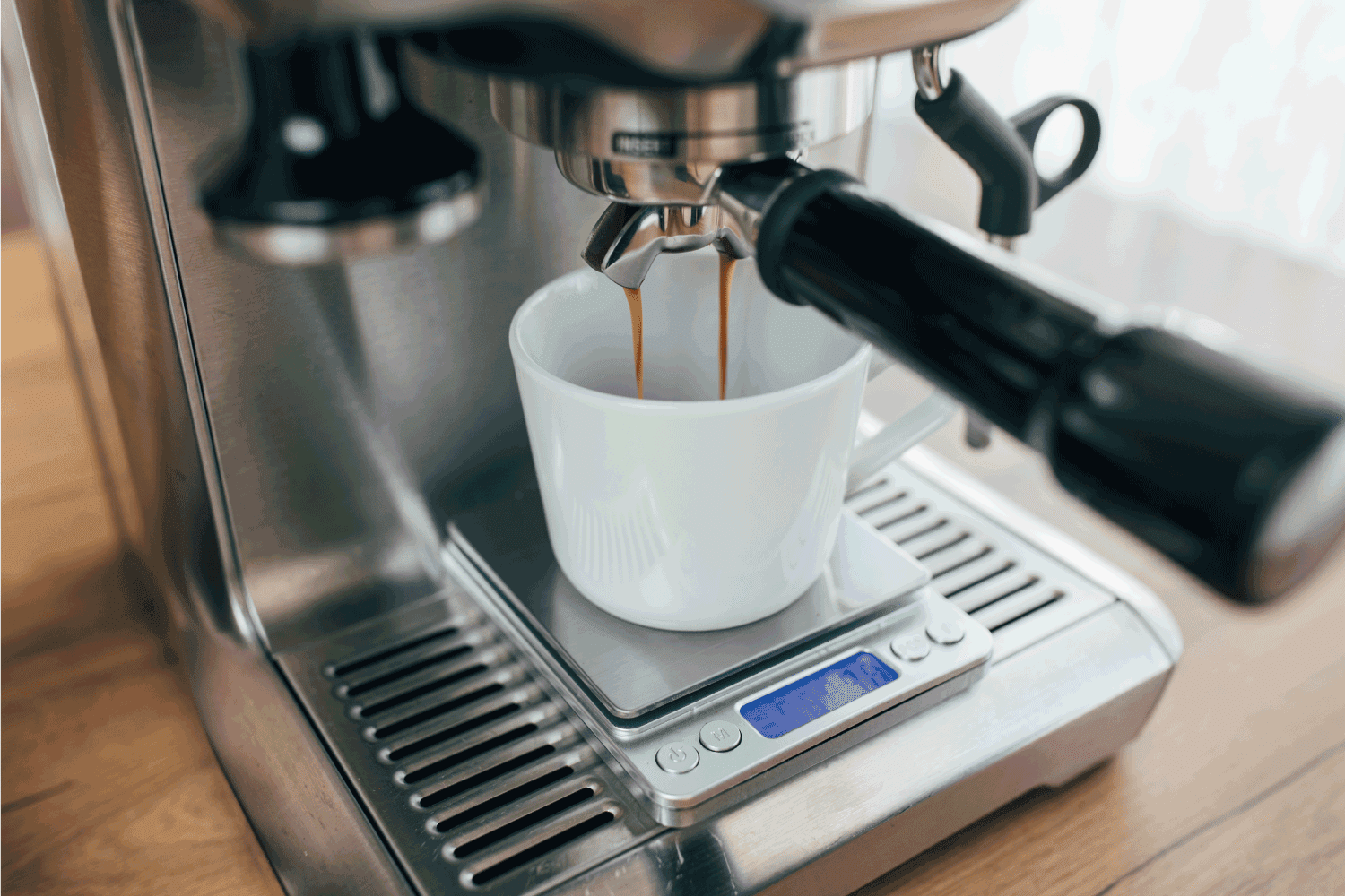 white cup on a small scale espresso machine dripping with coffee. Can An Espresso Machine Explode