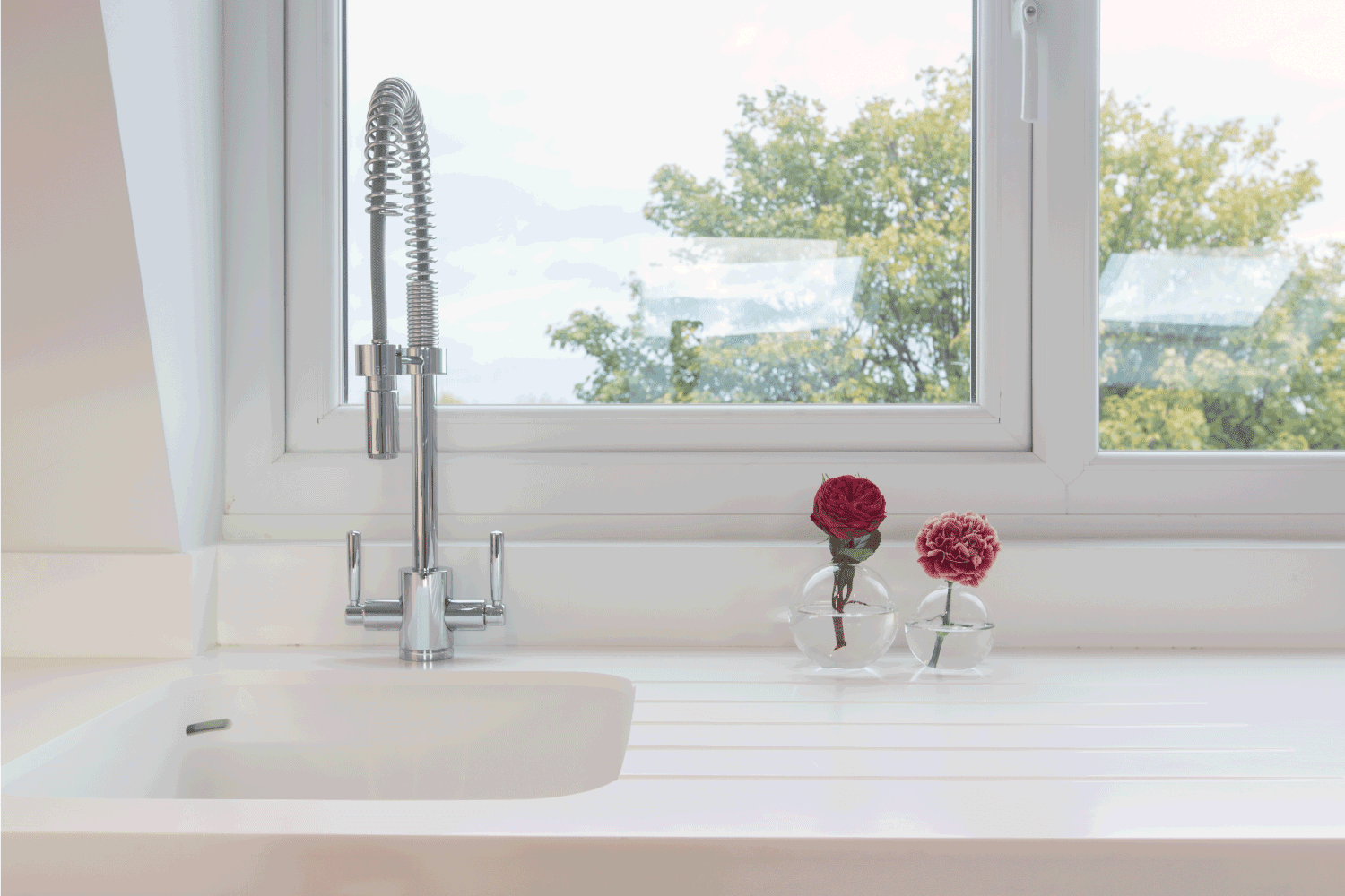 white kitchen sink on white countertop with window view