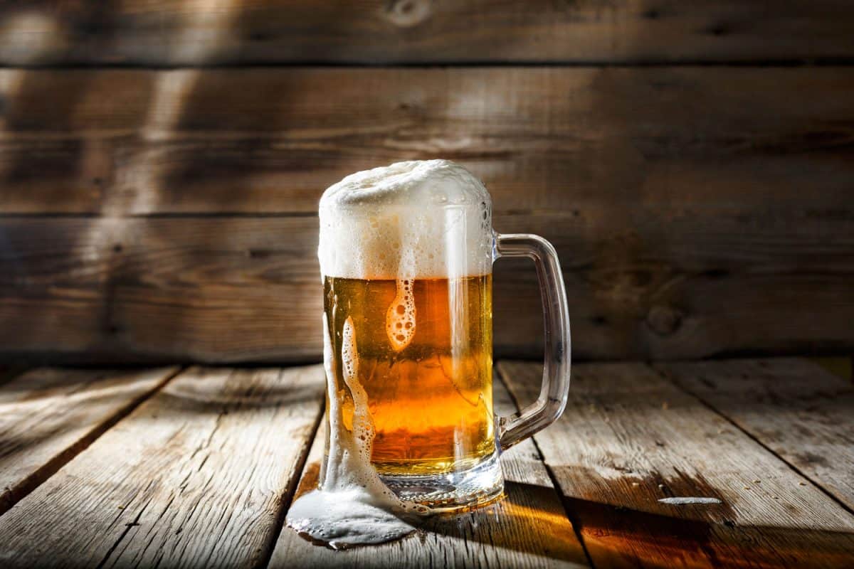A beer glass filled with light beer on the wooden table