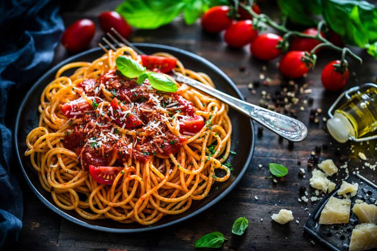 A plate full of delicious meatball spaghetti with ingredients scattered on the sides