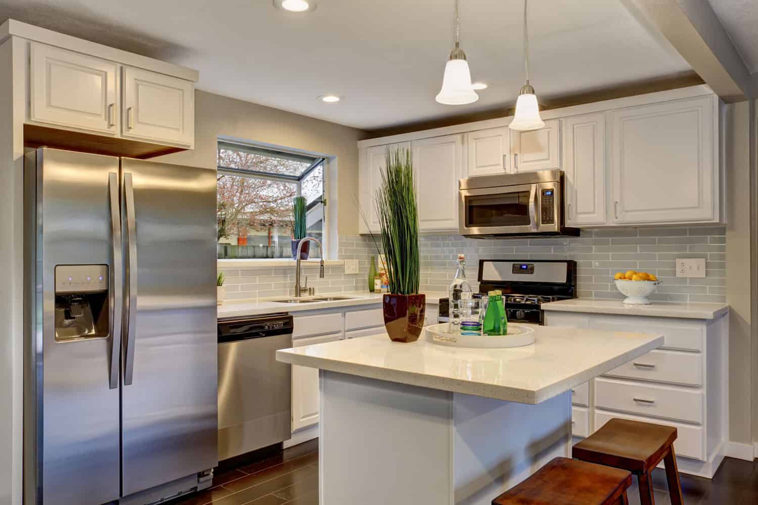 A spacious kitchen with a breakfast bar dangling lamps and a refrigerator on the corner, Do Refrigerators Have Wheels?