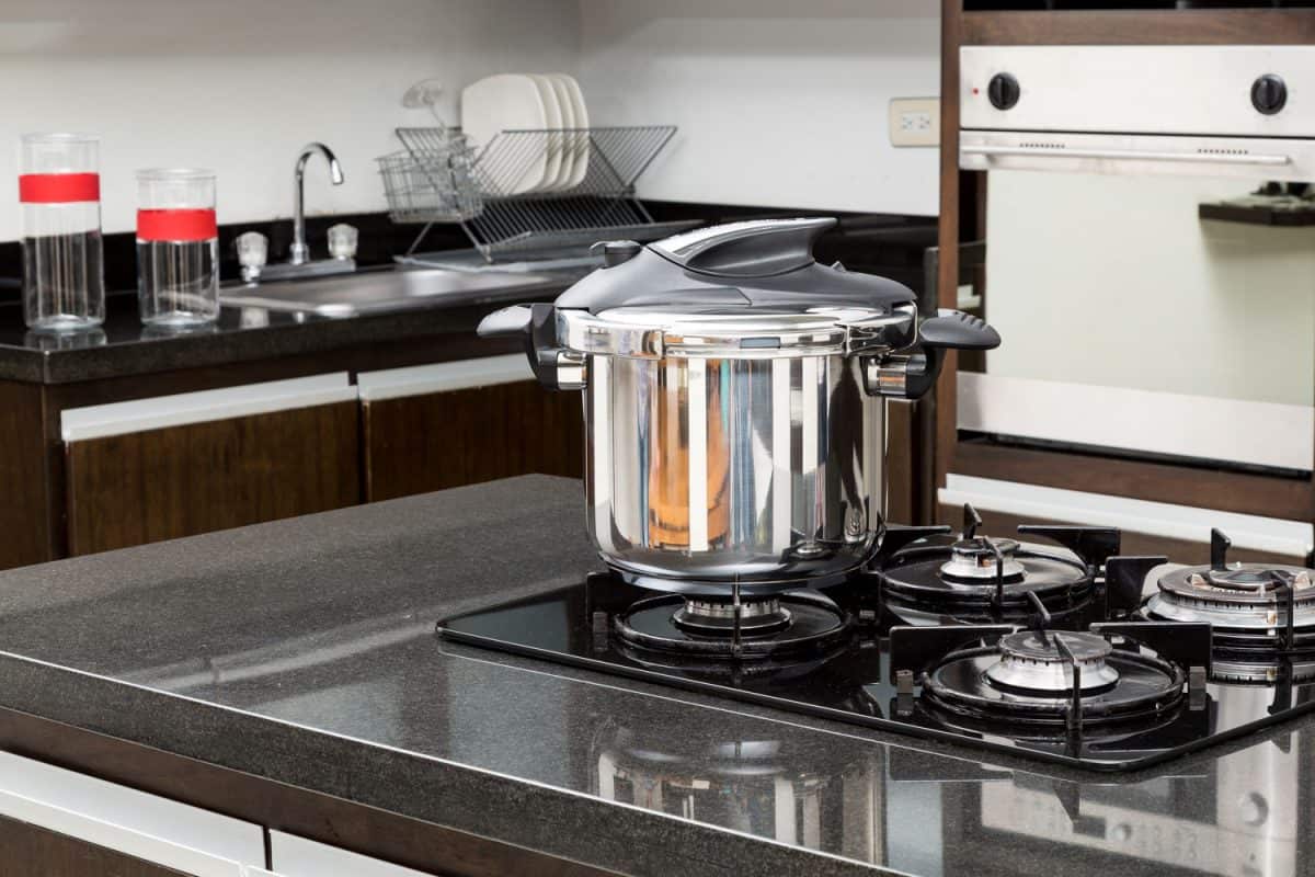 A stainless steel pressure cooker at the cooktop in the kitchen