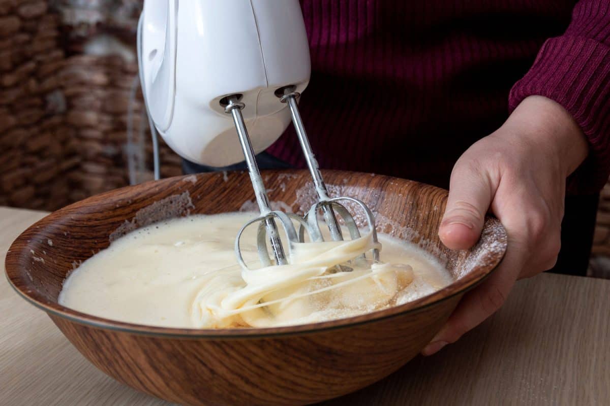 A woman using a hand mixer in the baking recipe