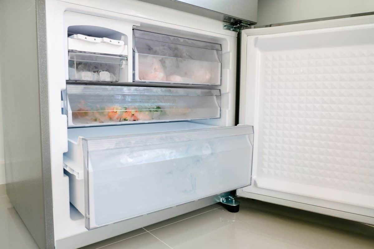 An opened small fridge with a chiller and freezer