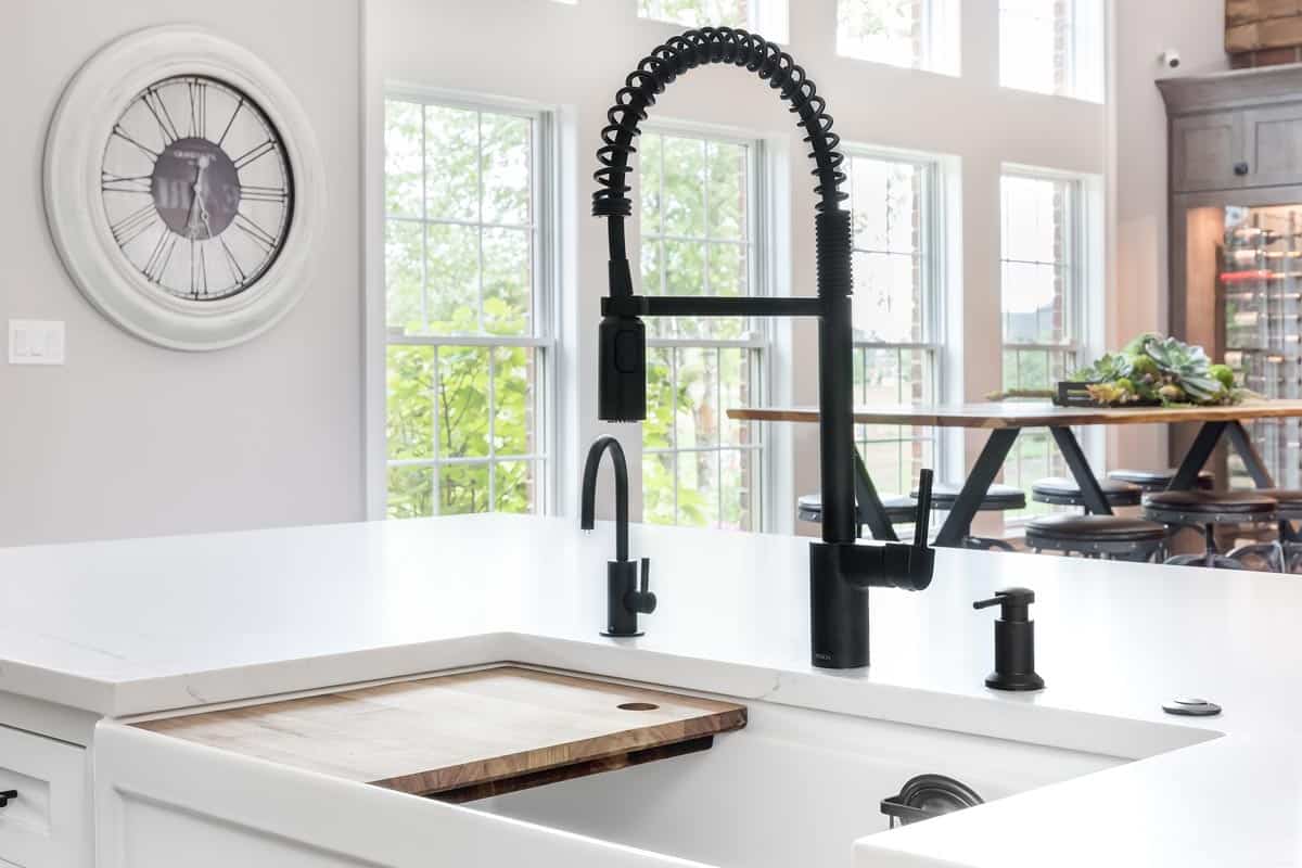 A beautiful kitchen detail shot of an apron sink with a black Moen faucet, How To Adjust Water Temperature On Moen Kitchen Faucet