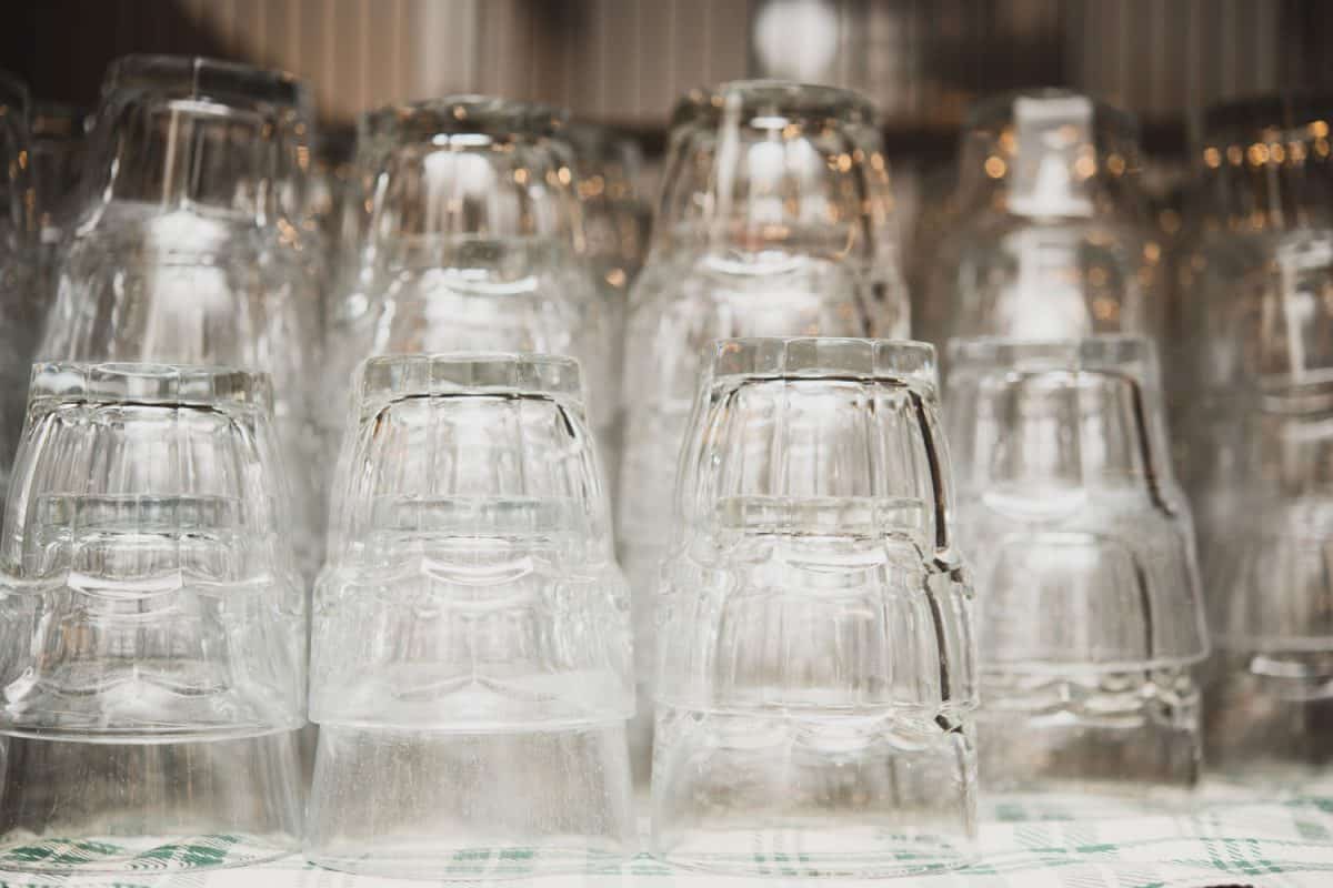 Close up of transparent clean glasses on a shelf, nested upside down stacked pile