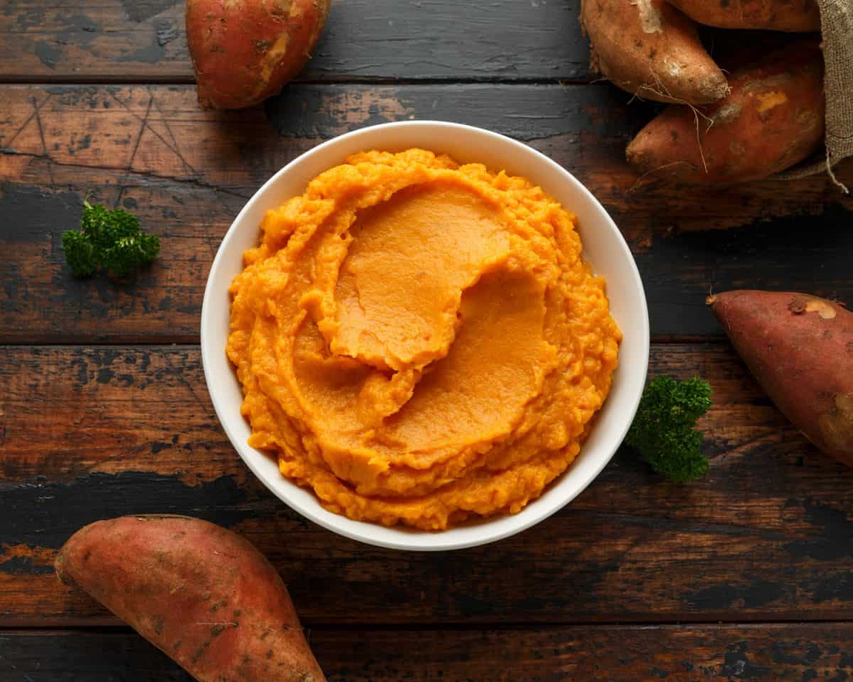 Mashed Sweet Potatoes in white bowl on wooden rustic table. Healthy food.
