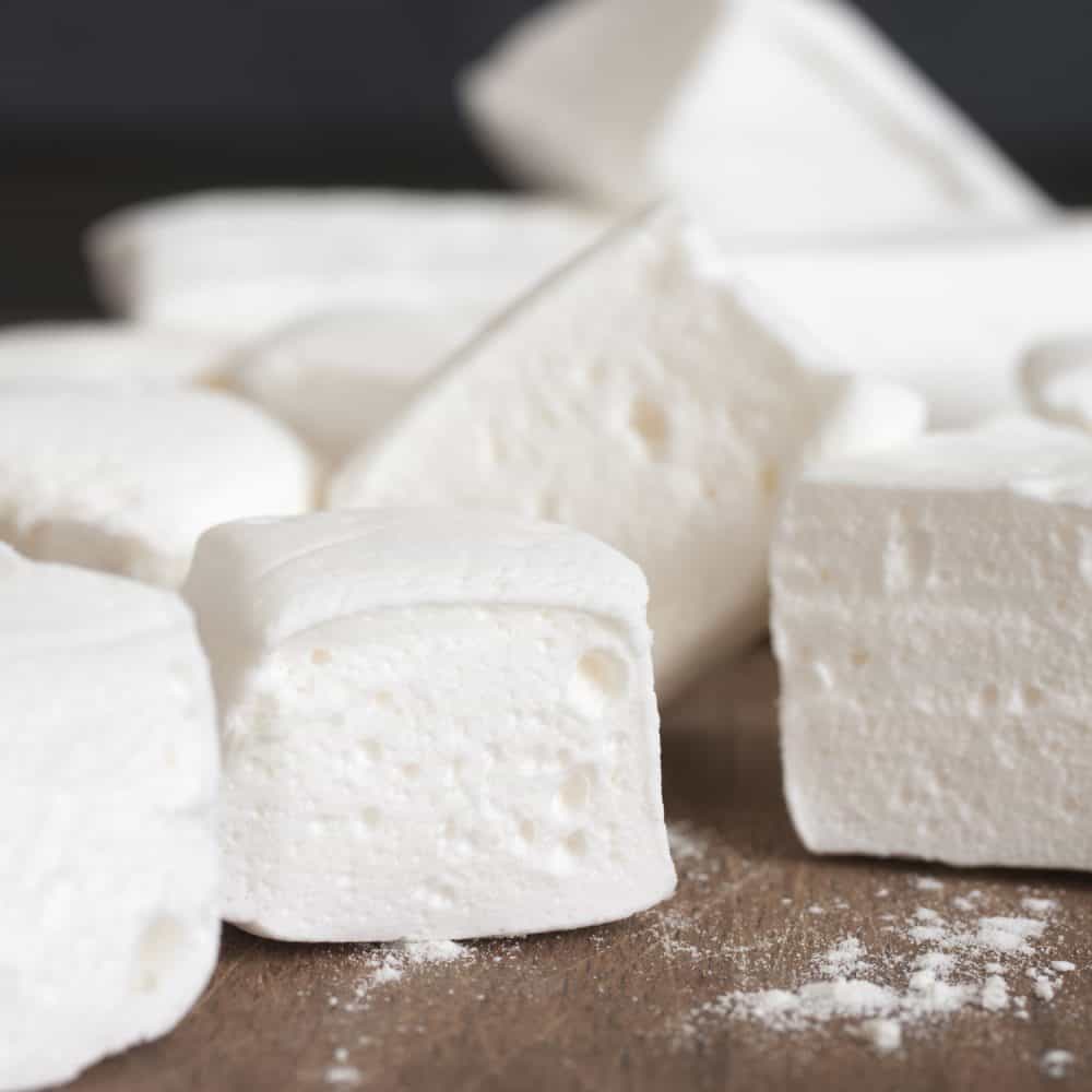 Pile of white homemade marshmallow close-up on wooden cutting board.