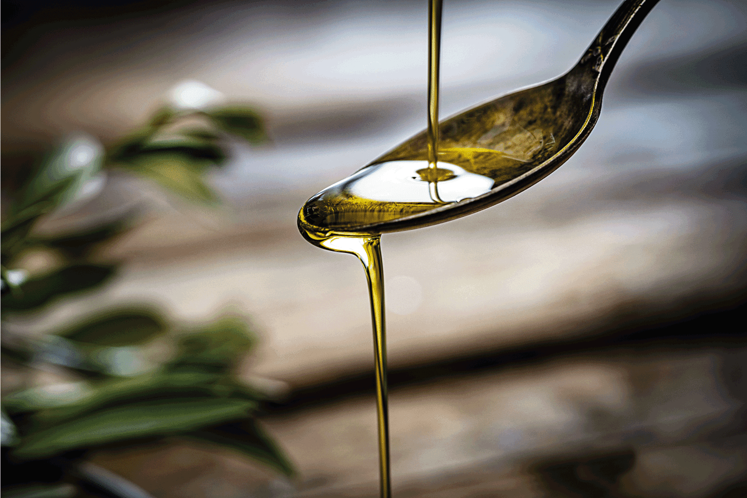 Pouring extra virgin olive oil on a vintage metal spoon