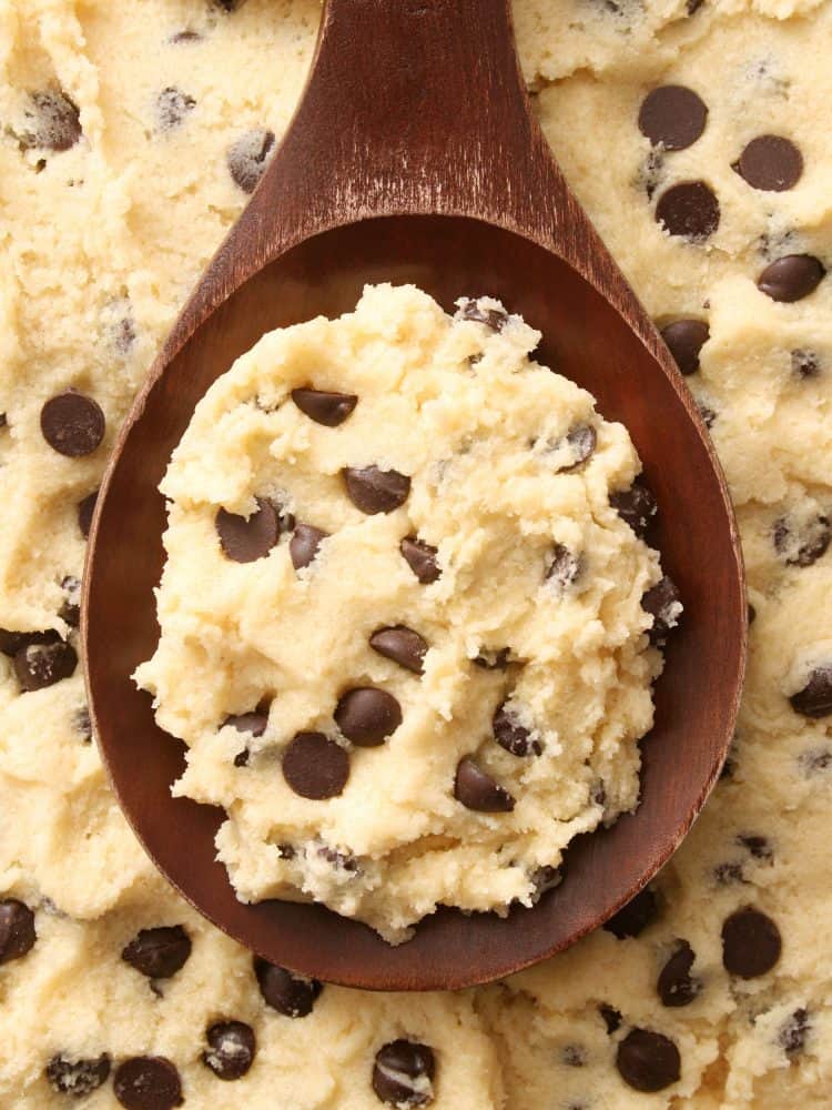 Top view of wooden spoon full of cookie dough with chocolate chips for baking