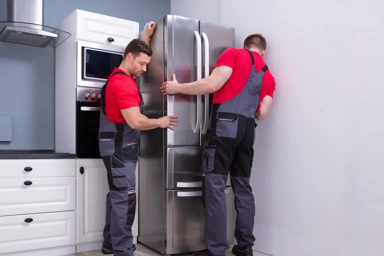 Two male move modern steel refrigerator in kitchen, Does A Refrigerator Typically Stay With The House?