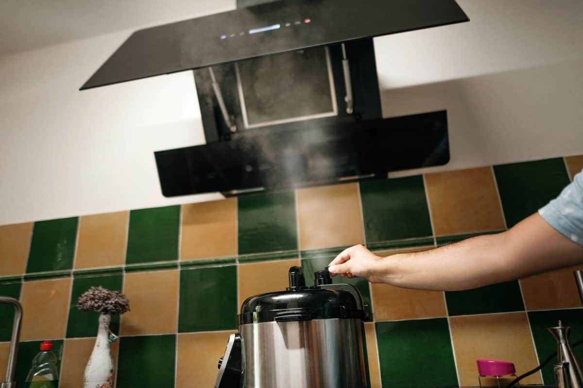 Woman removing the cap of the pressure cooker in her cooktop