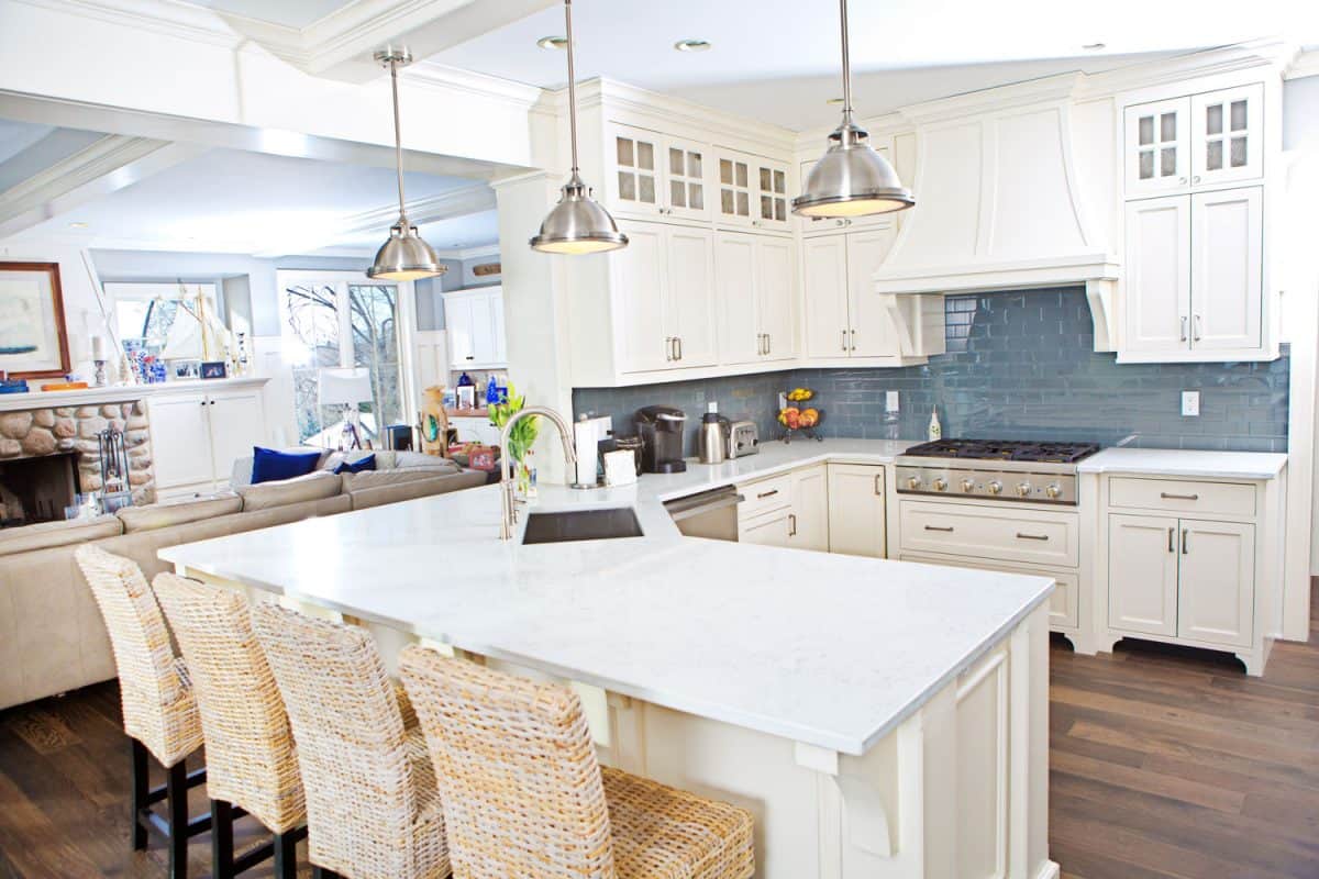 A gorgeous and brightly lit kitchen with white cabinets and cupboards and breakfast bar