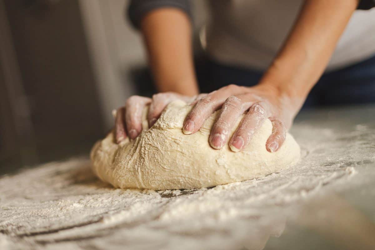 A woman making pizza dough on the table