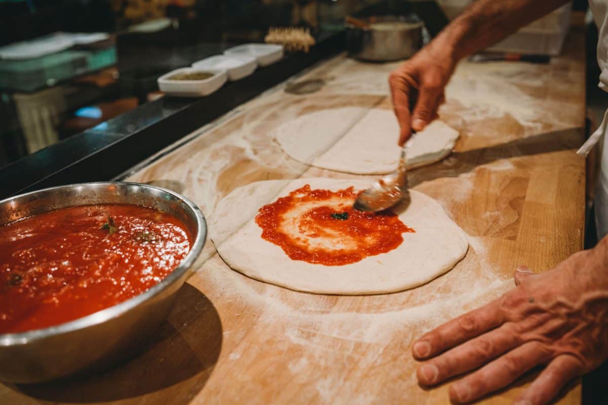 Chef spreading tomato sauce in the pizza dough