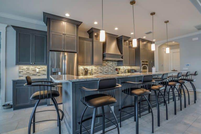 Dark gray cabinets and pendant lights adorn this classy kitchen, Should Bar Stools Match Your Dining Chairs?