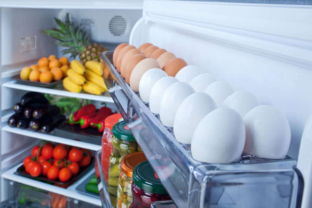 Eggs placed on the egg tray along with other fruits and vegetables inside the fridge