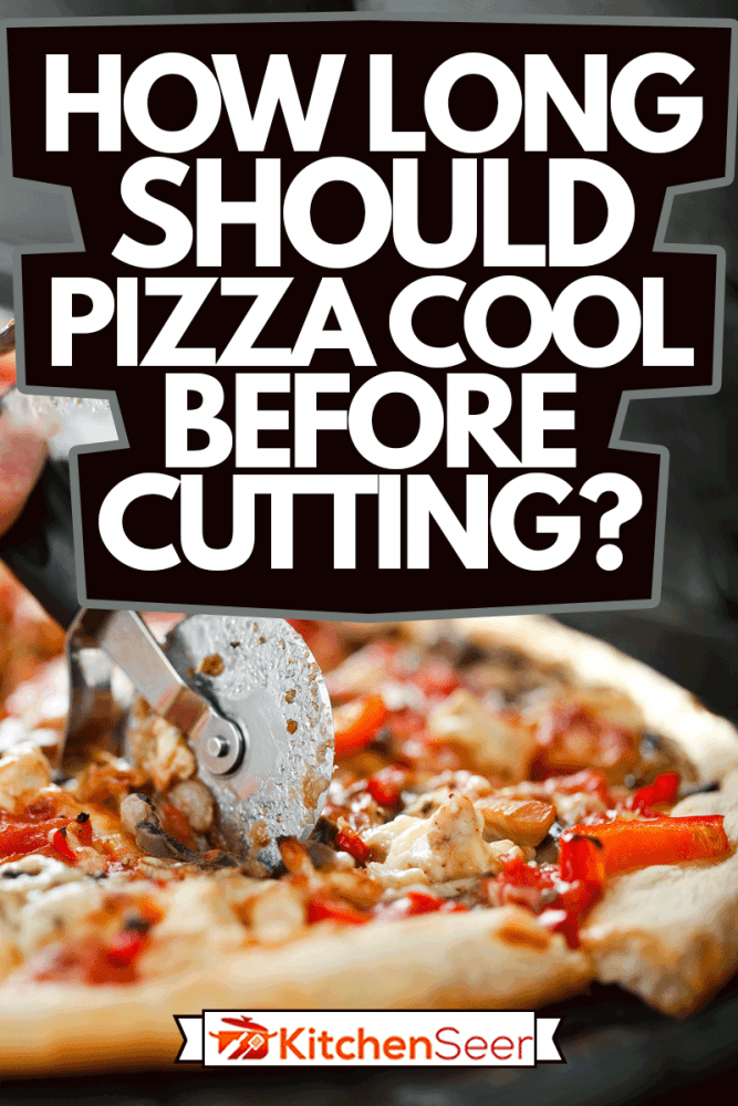 Close-up of pizza on cutting board that chef cuts into pieces with cutter, How Long Should Pizza Cool Before Cutting?
