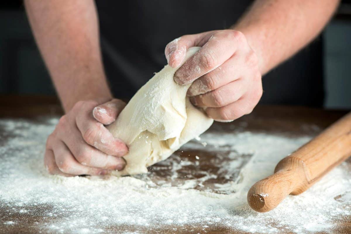 Man chef preparing bread dough on wooden table
