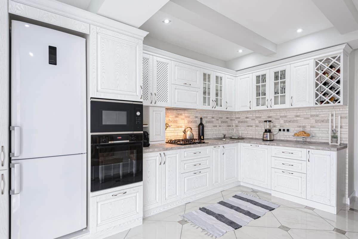 Modern white themed kitchen with white cupboards and cabinets with a huge white fridge