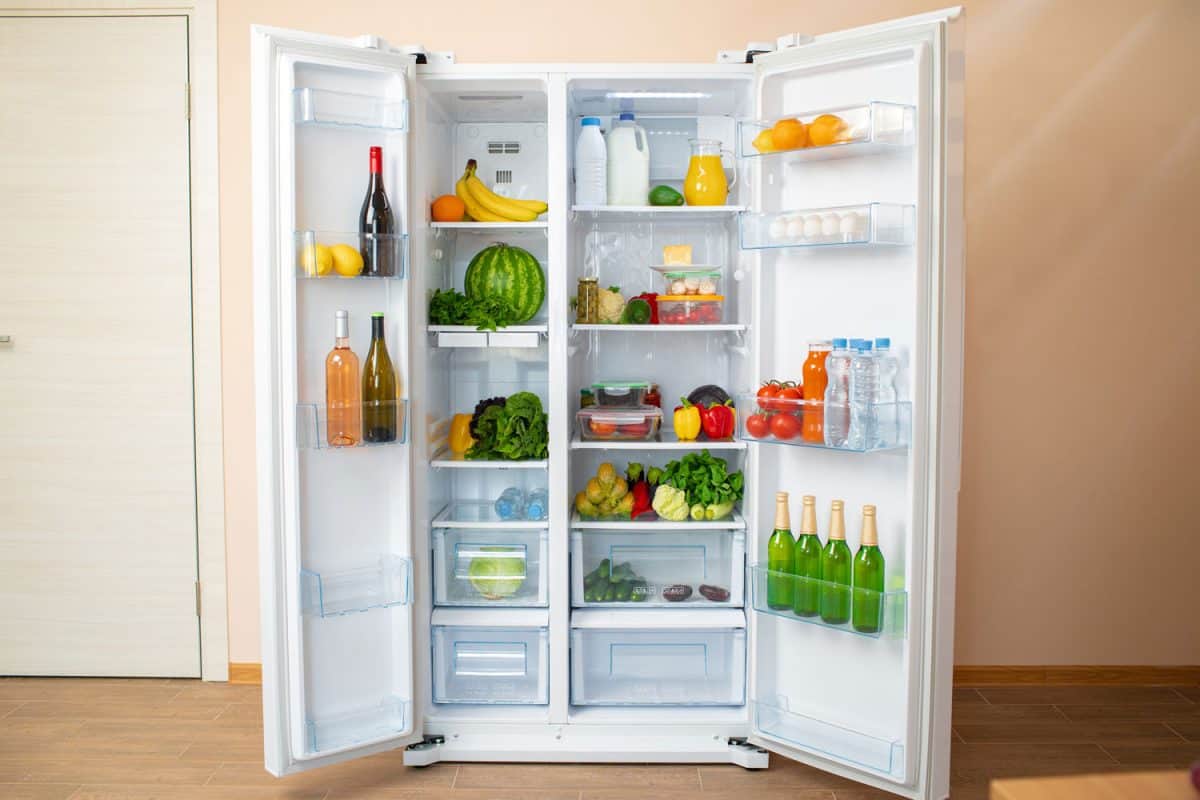 Open fridge full of fresh fruits, vegetables and drinks