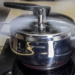 A pressure cooker releasing hot steam, Can You Use A Pressure Cooker On An Electric Stove?