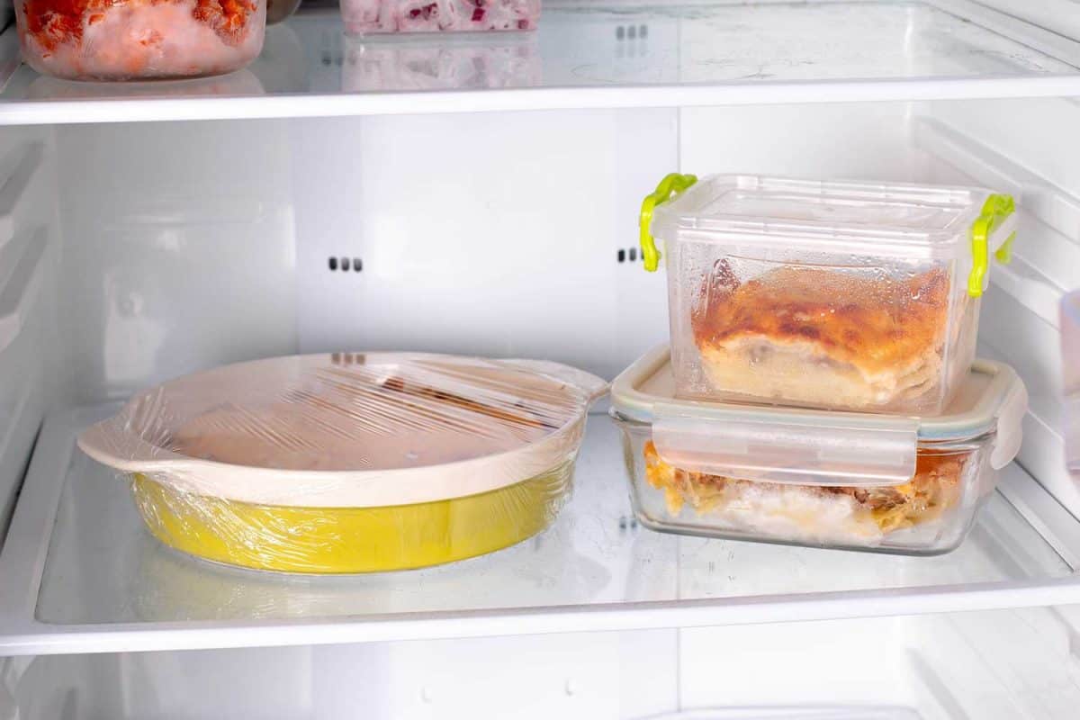 Ready frozen food in containers and in a baking dish on the refrigerator shelf