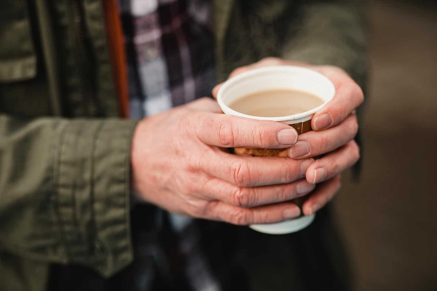 Senior man holding a cup of tea to keep his hands warm in winter