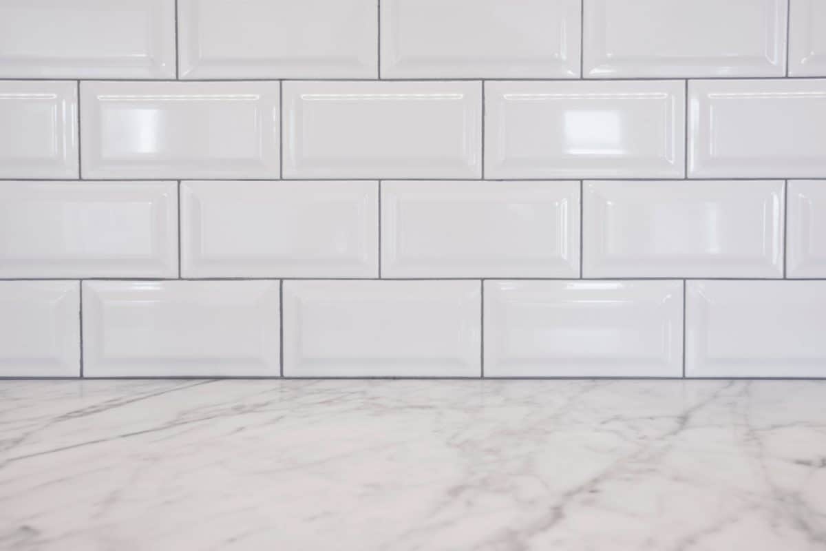Shiny small tile backsplash with a marble countertop in the kitchen