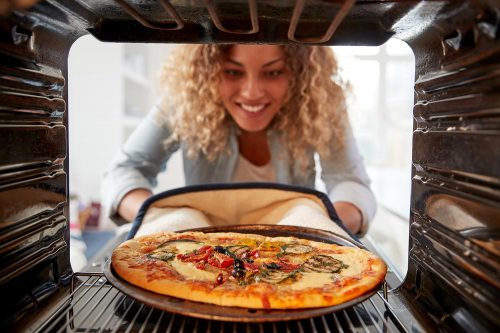  Woman cooks fresh pizza in oven