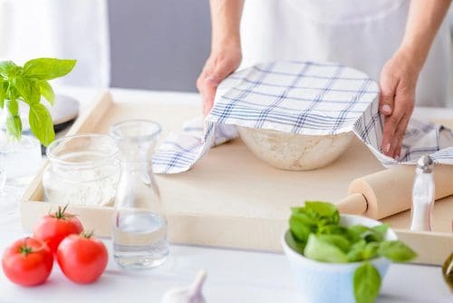 Woman covering yeast dough with towel