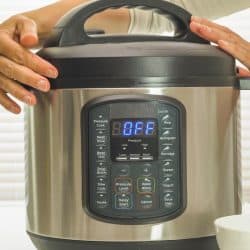 A woman holding the pressure cooker on kitchen table, Cuisinart Pressure Cooker Keeps Shutting Off - What To Do?