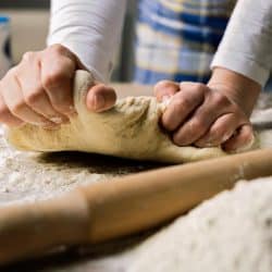 A woman making dough from flour ,milk and eggs on wooden table, For How Long Should You Knead Pizza Dough?