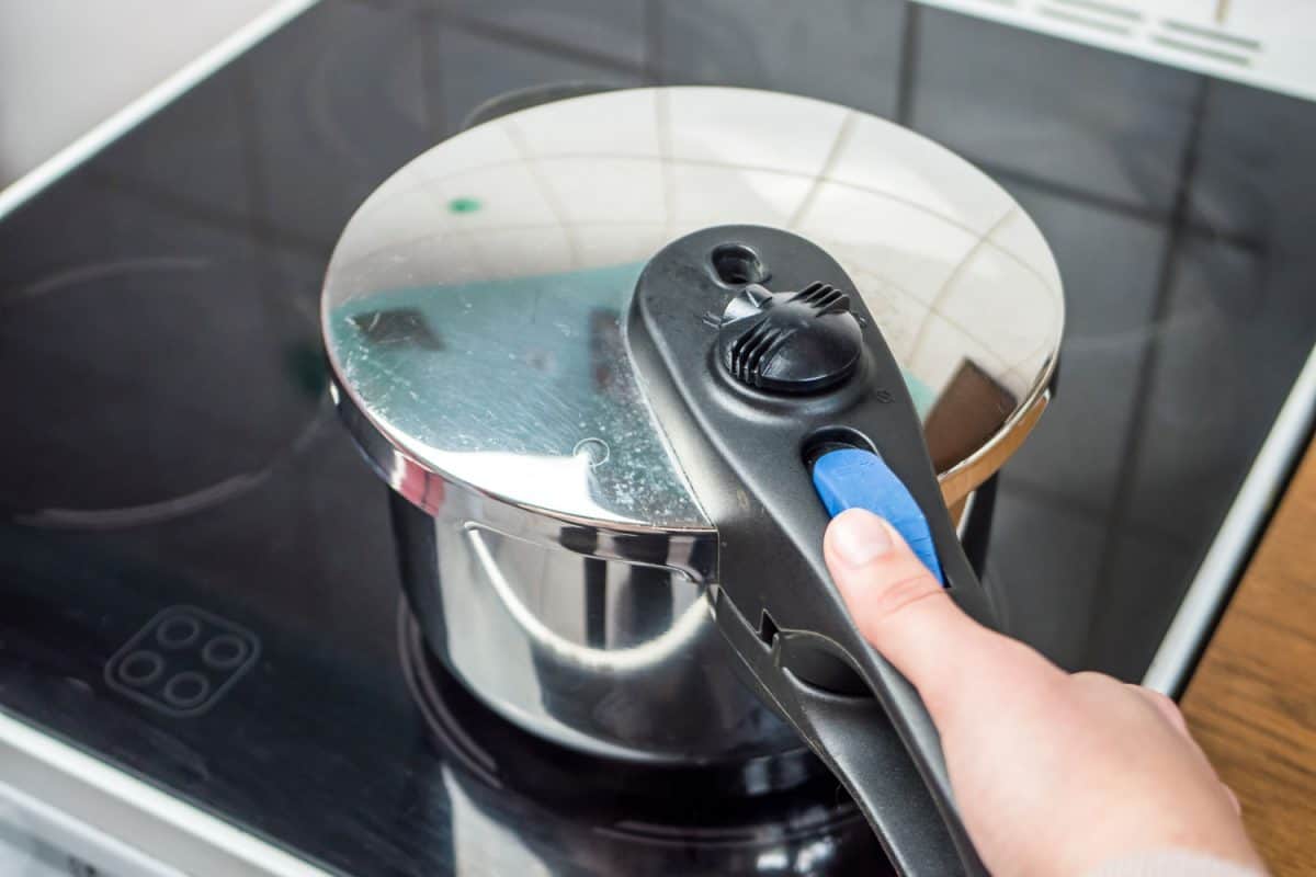 Woman placing a pressure cooker on the glass cook top