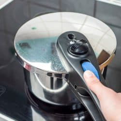 Woman placing a pressure cooker on the glass cook top, Does A Futura Pressure Cooker Whistle?
