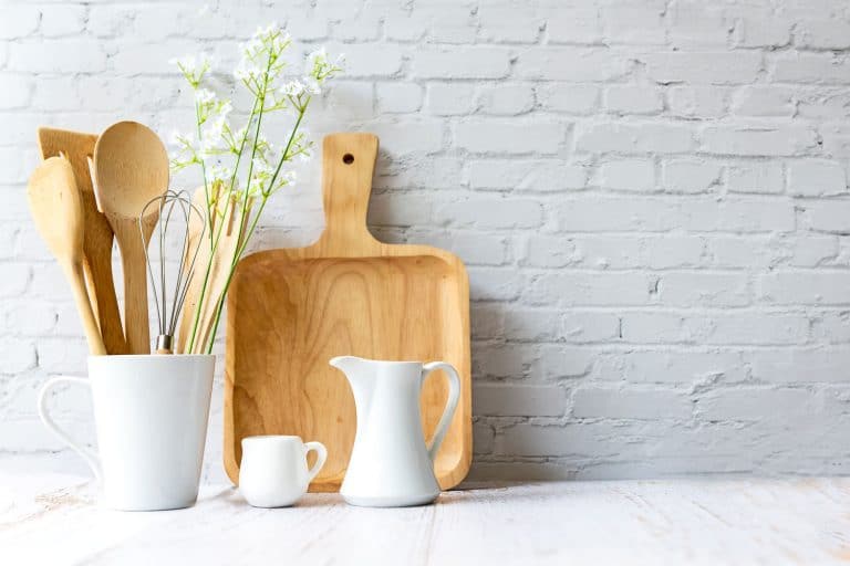Wooden kitchen utensils in the kitchen with a white brick backsplash, Does Kitchen Backsplash Need Trim Or Edging?