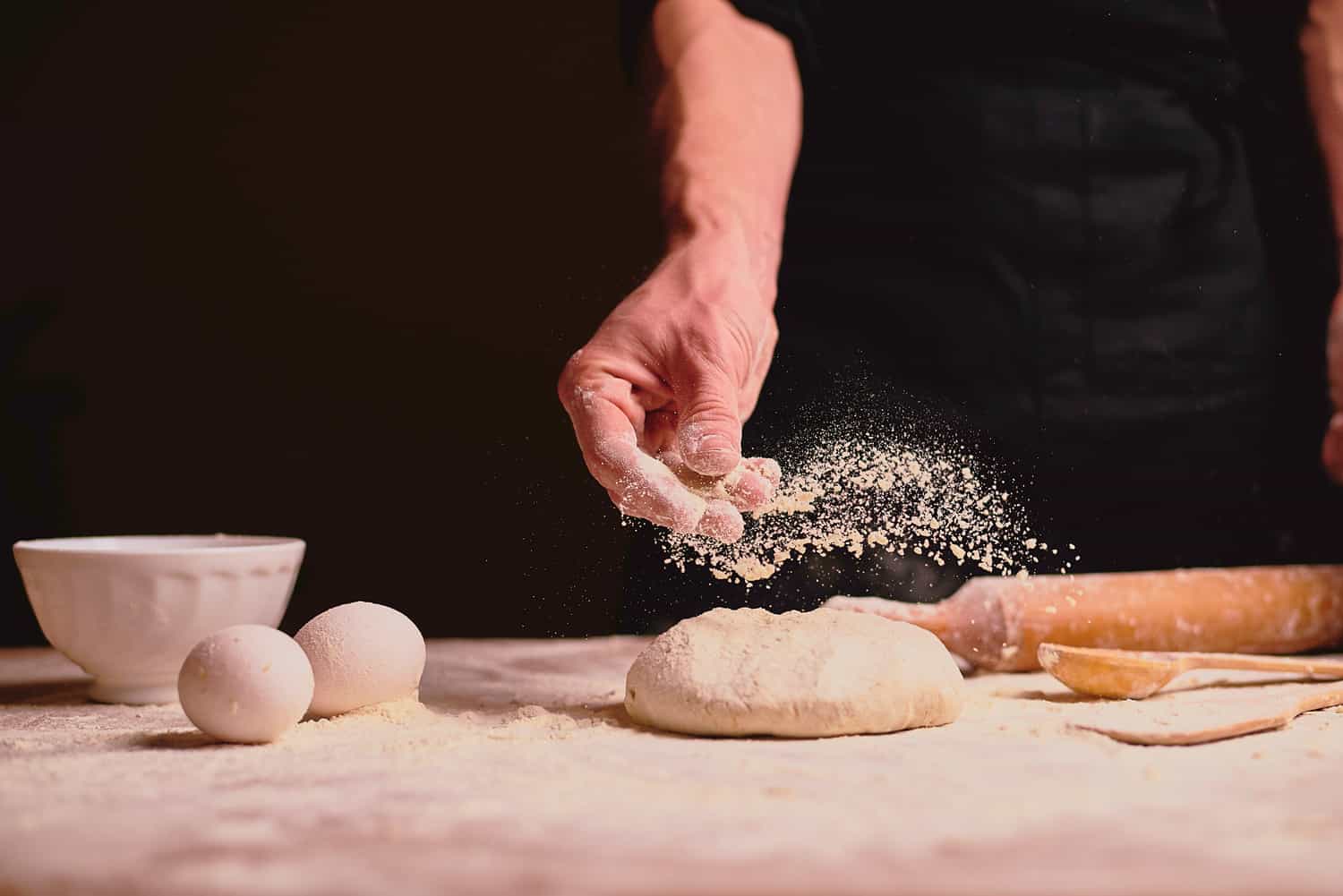 knead the dough, cook the dough on a dark background.