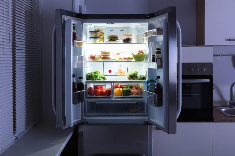 Open refrigerator full of juice and fresh vegetables in kitchen, Do Refrigerators Run Better Full Or Empty?