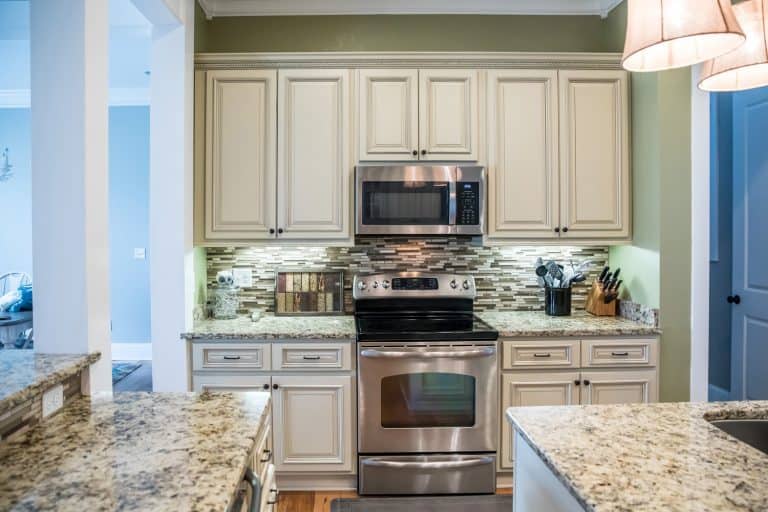 A small appliance microwave in a green kitchen with cream colored cabinets in a new construction home with granite countertops and lots of cabinets and storage space - What Color Walls Go With Cream Cabinets