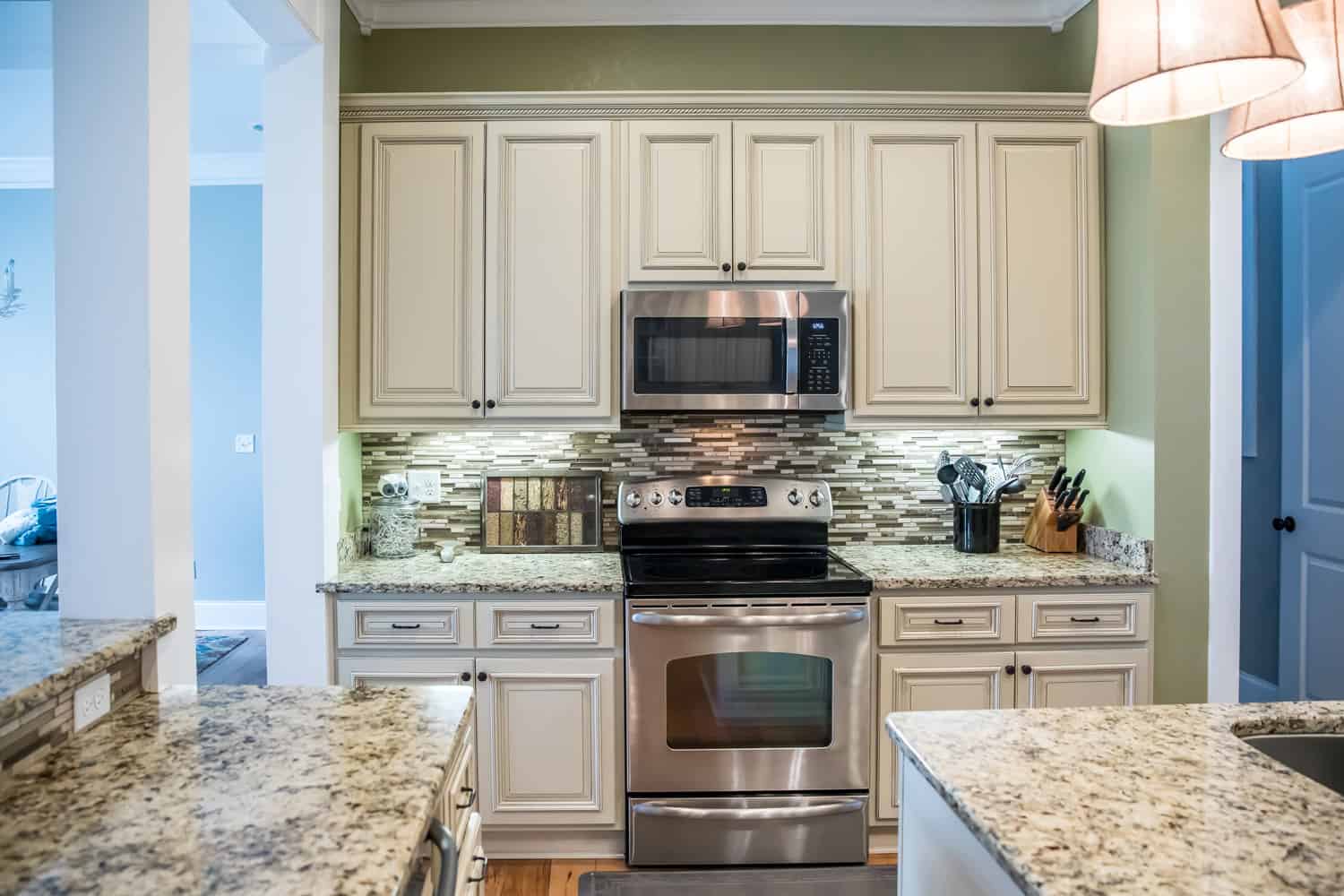 A small appliance microwave in a green kitchen with cream colored cabinets in a new construction home with granite countertops and lots of cabinets and storage space