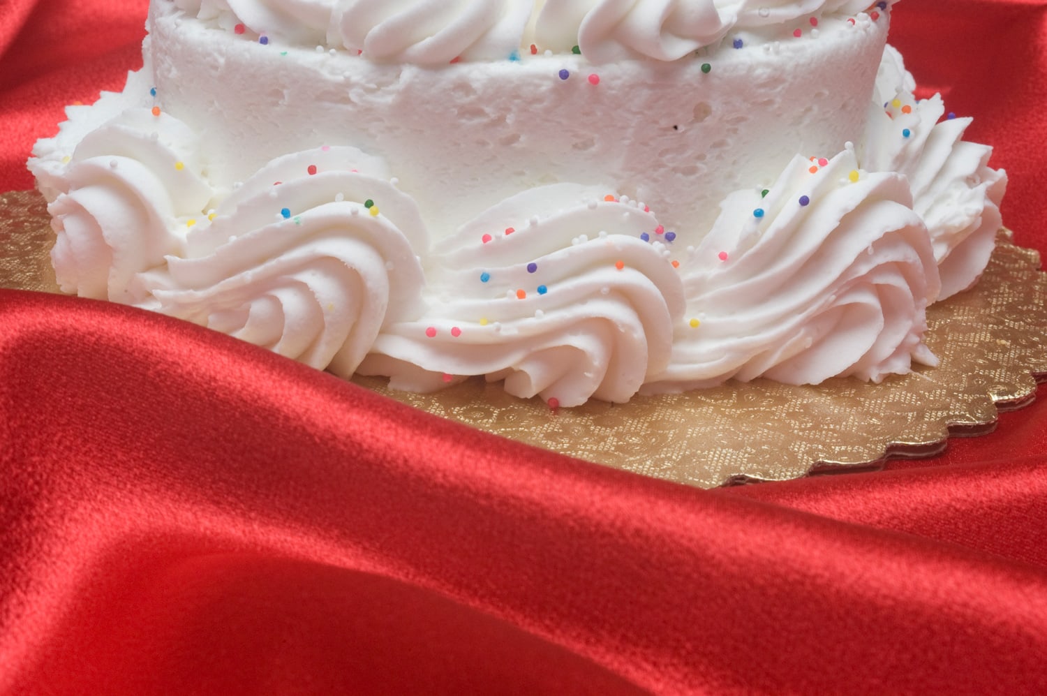 A frosted cake amongst waves of red satin cloth.