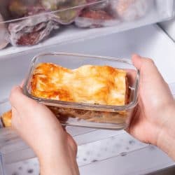 A person is taking a container of frozen casserole or lasagne out of the freezer - Left Lasagna Out Overnight - What To Do Now