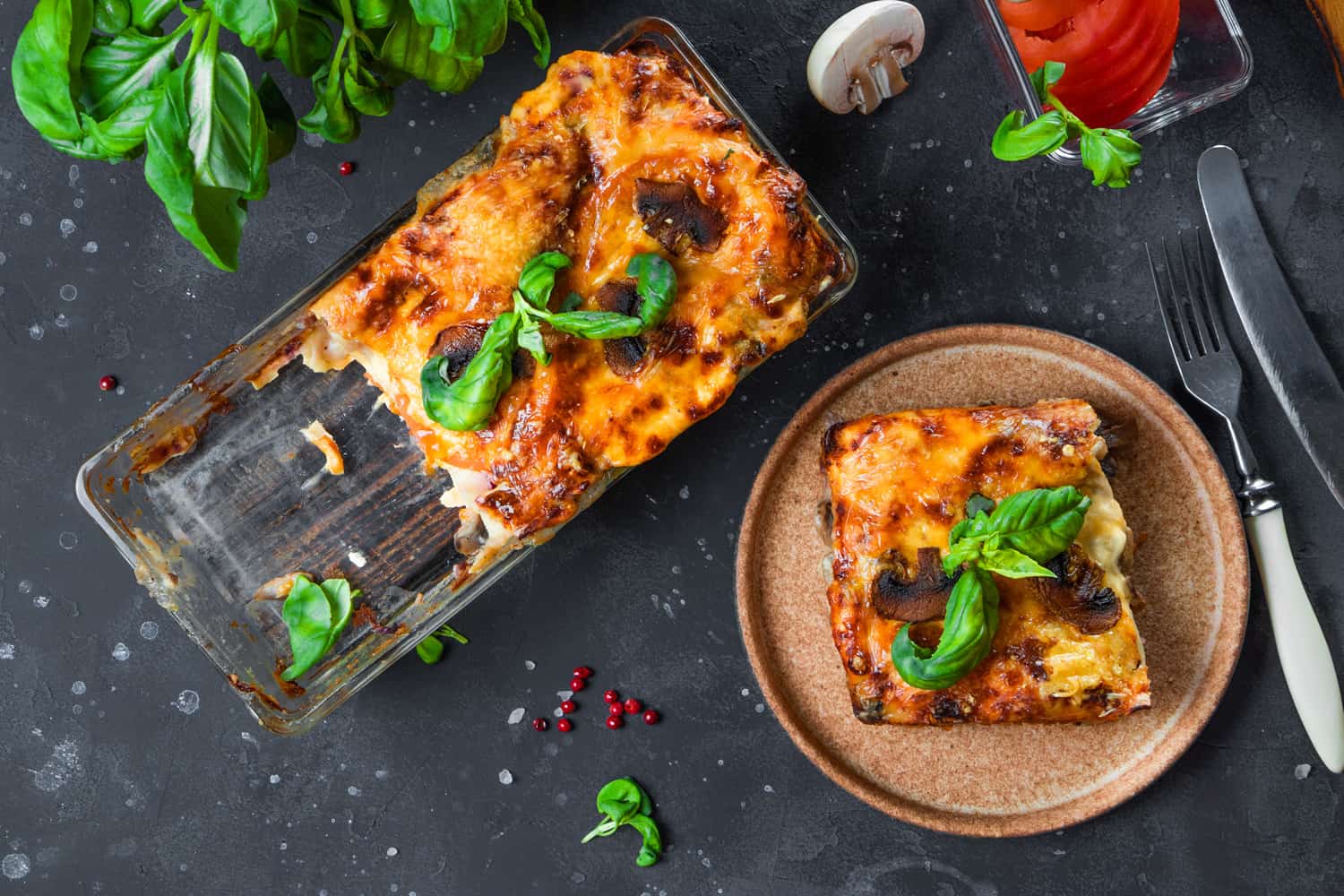 A piece of vegetarian lasagna with mushrooms, tomatoes and basil, top view. High quality photo