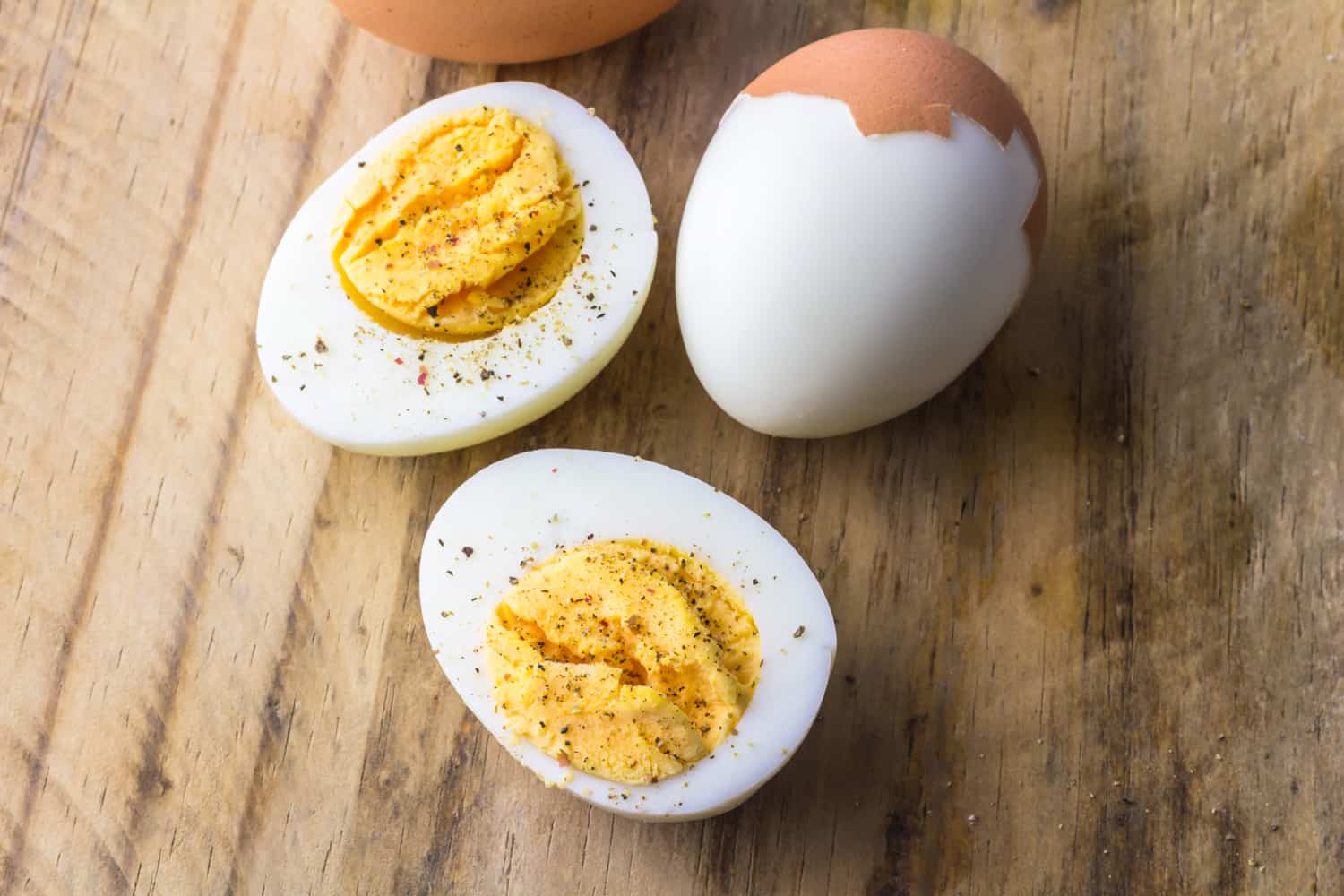 Boiled chicken eggs on wooden board with pepper flakes